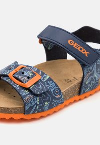 Sandalo per bambini con tomaia blu navy decorata con motivi astratti colorati, dettagli arancioni, chiusura a fibbia e suoletta in sughero testurizzato.