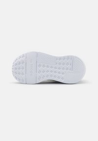 Suola di sneakers bianche in gomma testurizzata per la presa, con un motivo di battistrada circolare e marchio in rilievo. Finitura liscia senza accenti visibili.