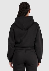 Black hooded sweatshirt with loose fit, long sleeves, and ribbed cuffs. Features a textured fabric and a kangaroo pocket at the front.