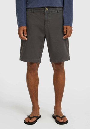 Sivé bavlnené šortky s rovnakým strihom, zapínaním na gombíky vpredu a vreckami. Nosia sa s čiernymi žabkami s jednoduchým dizajnom.