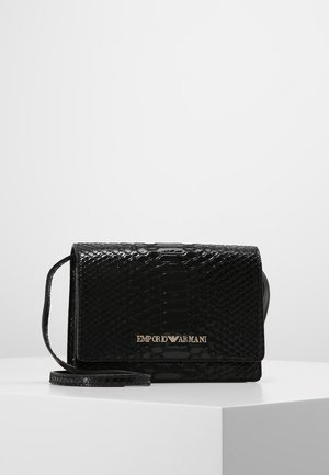 Sac à main en cuir de serpent noir avec un design structuré, accent logo doré et une bandoulière amovible pour un port polyvalent. La finition texturée rehausse l'attrait visuel.