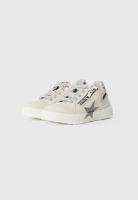 Beige sneakers with a textured finish, silver laces, side zipper, and a silver star accent on the outer side. Rubber sole, casual design.