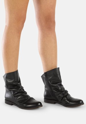 Bottines en cuir noir avec un design décontracté, fermeture éclair sur le côté et semelle plate. Présente des plis subtils et un détail du logo en forme de papillon.