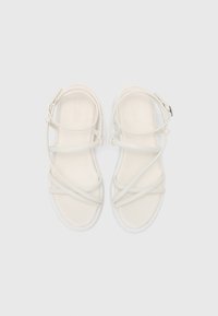 Sandale albe cu curele, cu talpă plată din cauciuc, având mai multe curele suprapuse și un detaliu cu cataramă. Suprafață netedă, design minimal.