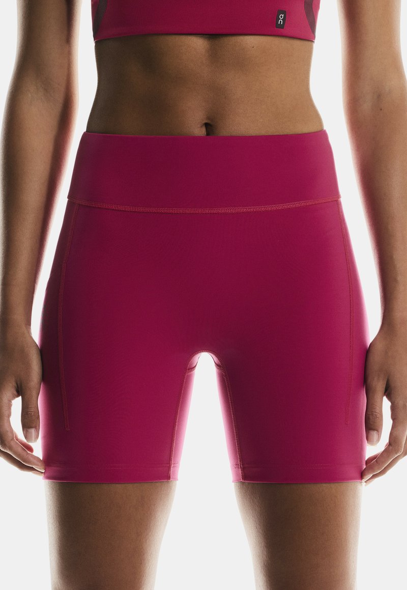 Fuchsia athletic shorts with a high waistband and flatlock seams; features a smooth, stretchy fabric and side pocket detail.