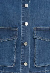 Denim jas in middelblauw, met zilveren drukknoopsluitingen en twee voorzakken met rechte randen en zichtbare stikdetails.