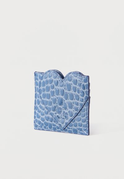 Μπλε δερμάτινο πορτοφόλι για κάρτες με σχέδιο κροκοδείλου και λεπτομέρεια με φάκελο σε σχήμα καρδιάς, τοποθετημένο όρθιο σε λευκό φόντο.