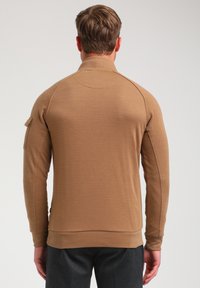 Bruine langmouwen pullover met een textuurafwerking, ritskraag en details van zijzakken. Aansluitend design met geribde manchetten en zoom.