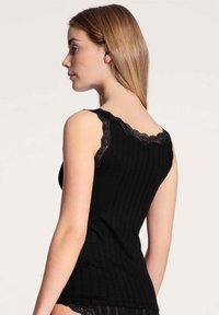 Zwarte geribbelde tanktop met kantafwerking langs de halslijn en bandjes, met een getailleerde silhouette en een zachte textuur.