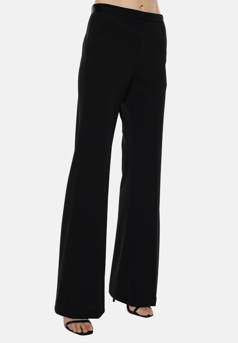 Pantaloni neri con gamba ampia, dalla texture liscia e vita elastica; presentano tasche laterali e un design fluido per un fit rilassato.