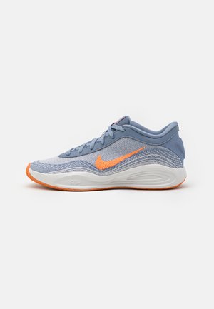 Baskets Nike avec un dessus en mesh bleu clair, des accents orange, un talon renforcé et une semelle extérieure texturée blanche.