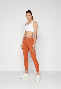 Nike Performance Leggingek - burnt sunrise/white