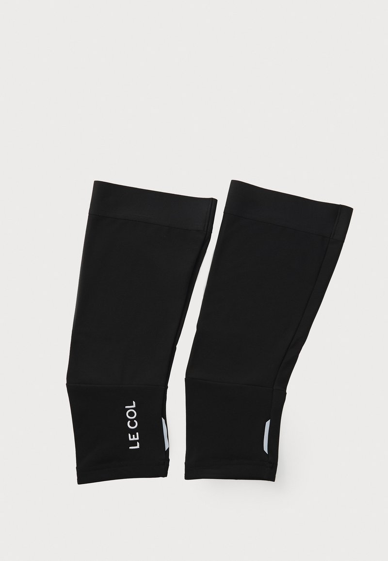 Black cycling leg warmers made of stretchy fabric. Features include a white logo and reflective accents on both sides.