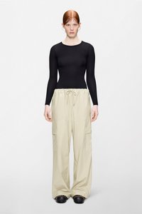 Μαύρο μπλουζάκι με μακριά μανίκια και μπεζ, γυαλιστερό, φαρδύ παντελόνι cargo με ελαστική μέση και κορδόνι. Διαθέτει πλαϊνές τσέπες και απαλό ύφασμα.