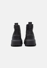 Černé kotníkové boty s hladkým textilním svrškem, texturovanou gumovou podrážkou, poutkem na patě a logem na zadní straně. Robustní design podpatku.