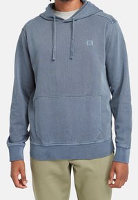 Sudadera con capucha en suave tejido azul desgastado. Cuenta con un bolsillo tipo canguro y puños y bajo acanalados para un ajuste cómodo. Detalle de marca simple.