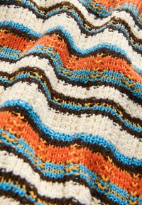 Pletená látka s vlnitými pruhy v krémové, oranžové, modré, hnědé a žluté barvě. Texturovaná příze s měkkým, útulným vzhledem.