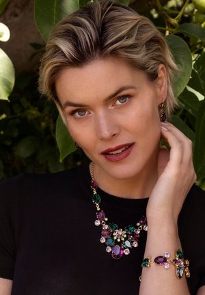 Collier et bracelet colorés avec des gemmes violettes, vertes et transparentes, rehaussés de accents dorés. Textures lisses et un design floral audacieux.