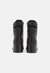 Stivaletti neri in pelle con punta rotonda, tomaia texture e chiusura con zip sul retro. Tacco a blocco per un supporto stabile.