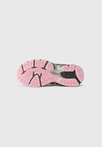Semelle de chaussure de course en caoutchouc noir et rose. Présente un motif de traction texturé, une semelle intermédiaire avec des accents argentés, et un relief prononcé pour une meilleure adhérence.