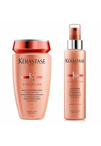 Kérastase hair care products: a pink shampoo bottle with a red lid and a matching pink spray bottle with silver accents, labeled "Discipline."