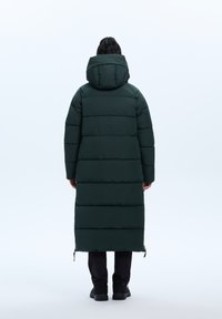 Grøn polstret frakke med hætte, der har et horisontalt kviltet mønster, lang længde og lynlås ved kanten. Blød tekstur og minimalistisk design.