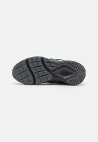 Black athletic shoe sole with textured rubber, featuring a pattern of deep grooves and a circular traction design. Nike logo embossed.