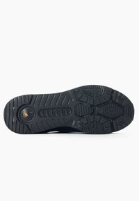 Suola di scarpa nera con una superficie in gomma testurizzata, dotata di un logo, scanalature per la presa e vari modelli di battistrada per la trazione.