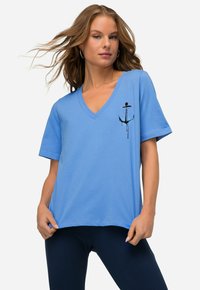 Lys blå v-hals t-shirt lavet af bomuld med en afslappet pasform. Har et sort og pink ankergrafik på venstre bryst. Korte ærmer.