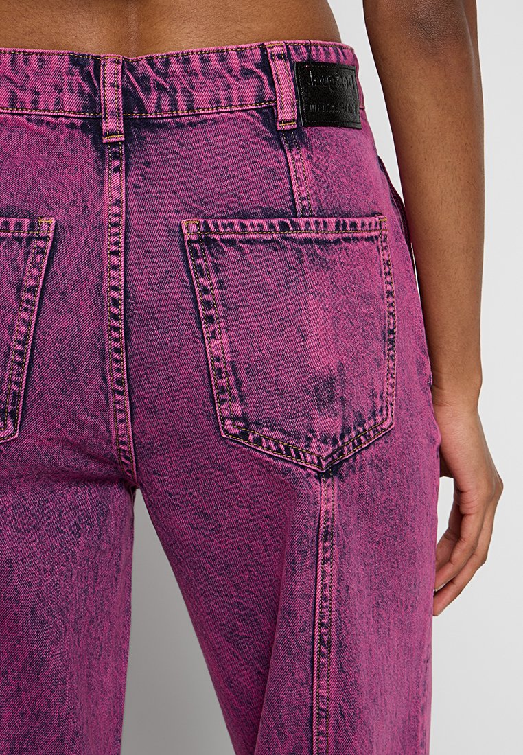 Jeans in denim rosa sbiadito con vita alta, due tasche posteriori e cuciture visibili. Presenta un'etichetta in pelle nera del marchio sul retro.