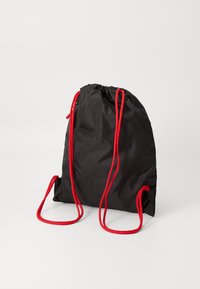 Black drawstring backpack made of nylon with bright red cords. Features a gathered top and a smooth texture. Compact and lightweight design.