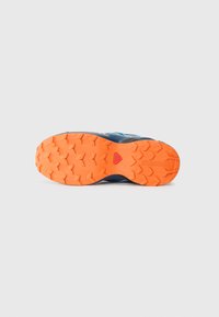 Blue trail running shoe with a textured orange outsole, featuring deep treads for grip and a durable upper with reinforced accents.