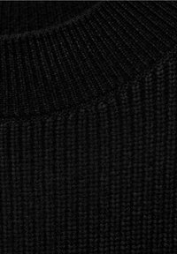 Schwarzer Strickpulloverkragen mit gerippter Textur und feinen vertikalen Linien, der ein weiches und gemütliches Material präsentiert.