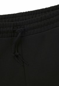 Sorte joggingshorts har en elastisk talje med snor og en glat tekstur, der fremhæver et enkelt, funktionelt design.