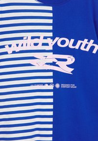 Material albastru cu dungi albe și albastre uni, cu text roz "wild youth" și stele decorative, plus text mic alb "Conceput pentru purtarea zilnică."