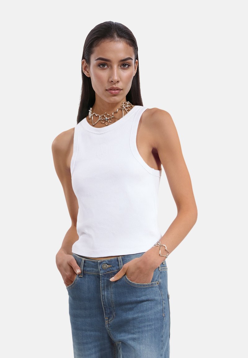 Witte geribbelde tanktop met een aansluitend ontwerp, ronde halslijn en brede armsgaten. Draag met blauwe denim jeans en een zilveren ketting met hartthema.