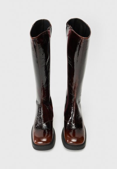 Μαύρες γυαλιστερές δερμάτινες μπότες μέχρι το γόνατο με τετραγωνισμένες μύτες και υφή. Διαθέτουν ελαφρύ τακούνι και φερμουάρ.