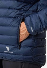 Giacca imbottita blu navy con design trapuntato, dotata di tasca laterale con zip e testo "PREMIUM DOWN" e "FP800" sulla manica. Texture liscia.