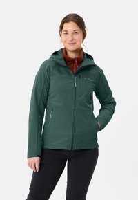 Giacca softshell verde con zip frontale, cappuccio regolabile e due tasche laterali, indossata sopra un maglione in pile rosso.