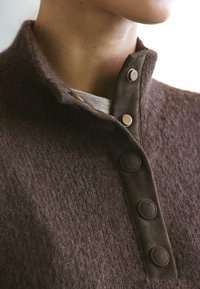 Pull en laine brun texturé avec un col montant et trois boutons, doté d'une doublure intérieure douce.