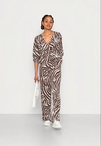 Conjunto de pijama solto, listrado em castanho e branco, com um top de decote em V profundo e calças de perna larga. Apresenta mangas longas e uma silhueta casual.