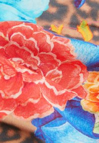 Tkanina w kwiatowy wzór w odcieniach czerwieni, niebieskiego i pomarańczy, o miękkiej fakturze i rozmytych krawędziach, z dużymi, wyrazistymi motywami kwiatowymi.