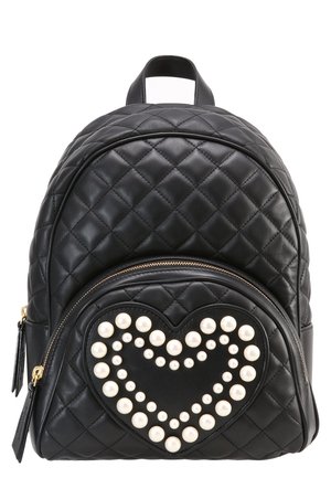 Sac à dos noir matelassé avec poche avant ornée d'un cœur délimité par des clous en perles blanches et des détails de fermeture éclair dorée.