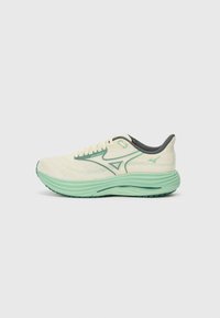 Zapatilla de running ligera en color crema con detalles en verde, parte superior de malla, collar acolchado y suela texturizada. Presenta un diseño aerodinámico y cordones.