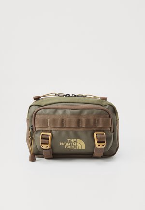 Sac bandoulière en nylon vert et marron avec deux clips à l'avant, une sangle latérale et un logo jaune sur le devant. Dispose d'une fermeture éclair et d'accents texturés.