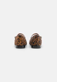 Mocasines de piel estampados con leopardo, con una textura suave, suelas de charol negro y una forma redondeada. Detalles de hardware dorado decorativos en los laterales.