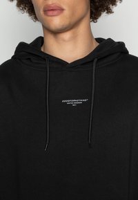 Felpa con cappuccio nera in cotone con logo frontale bianco con la scritta "GOODFORNOTHING". Presenta coulisse e vestibilità regolare.