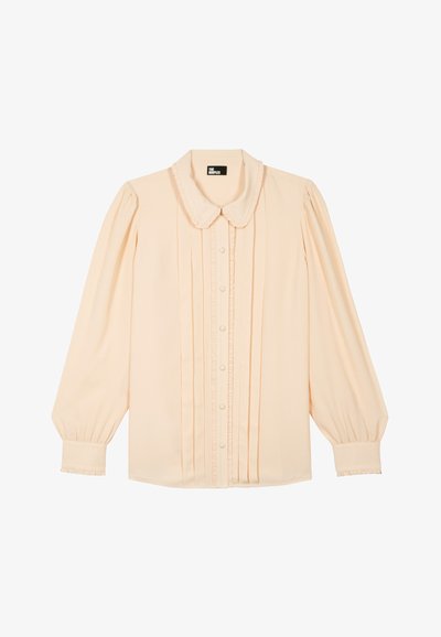Blusa beige de manga larga con tapeta de botones con volantes, mangas abullonadas y cuello redondeado de la marca The Kooples.