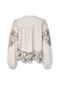 Blouse crème à manches volumineuses avec motif floral brodé en brun foncé le long du bas et des manches. Texture douce en coton.