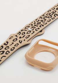 Beige silicone watch strap with black leopard print cutouts and silver hardware, paired with a matching tan case.